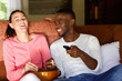 © mimagephotos - Happy young couple enjoying watching movie at home