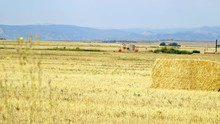 Scene Focus Moves From A Straw In The Foreground To A Large Square Hay Bale.
