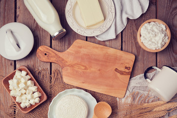 Wall Mural - Milk, cheese and butter with cutting board on wooden background. View from above. Flat lay