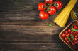 © Vladislav Noseek - Italian cooking ingredients. Dry pasta, olive oil, fresh tomatoes and arugula salad on wooden backdrop, table top view, copy space