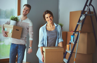 Happy young couple unpacking or packing boxes and moving into a new home