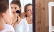 © shefkate - Beautiful girls looking in the mirror and applying cosmetic with a big brush