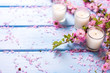 Background  with sakura  pink flowers  and candles on blue woode