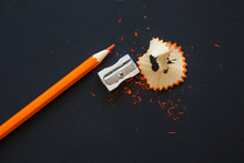 Sharpener And Orange Pencil Shavings On Black