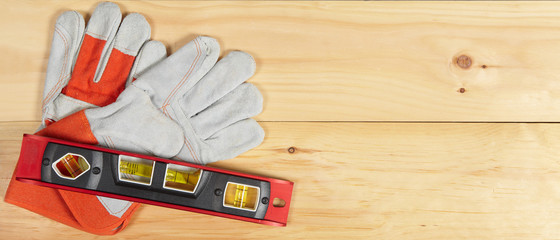 Wall Mural - Level and gloves wrench on wooden background