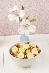 Wall Mural - corn flakes bowl with sliced banana with white lily flower on a vase