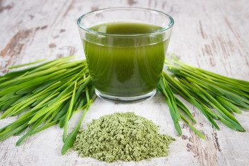 Heap of young powder barley, barley grass and beverage on old wooden background