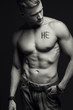 Handsome muscular male model with intense glance posing over grey background. Perfect body with the inscription 