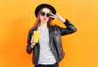 © rohappy - Fashion pretty woman in black rock style having fun over orange