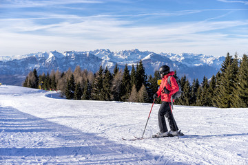 Female skier enjoys view on italien slopes with beautiful mountains in distance.