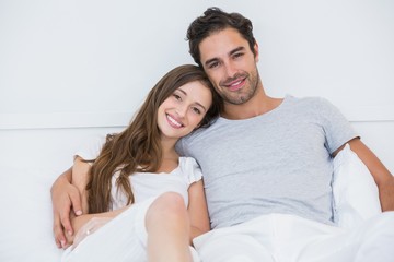 Wall Mural - Portrait of happy couple sitting on bed