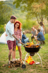 Wall Mural - Young curly ginger girl hug boyfriend near grill