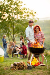 Wall Mural - Guy put log on grill fire and hug curly girl