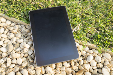 digital tablet on grass and stone