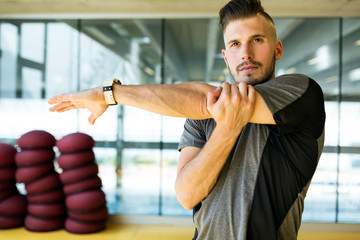 Wall Mural - Handsome young man doing muscular exercise in gym.