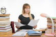 © madhourse - Joyful girl behind a desk littered with books, looking at the paper in his hands