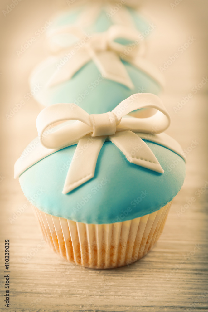 Tasty cupcakes with bow on light background