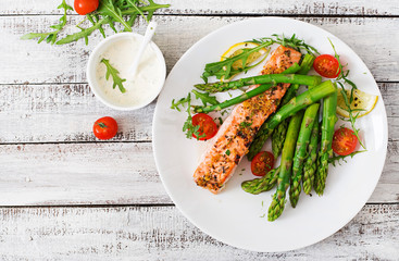 baked salmon garnished with asparagus and tomatoes with herbs. top view