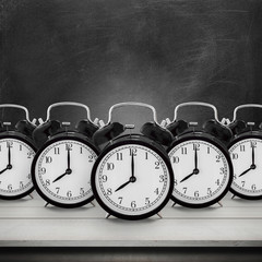 Five of vintage alarm clock on wood table desk over chalkboard b