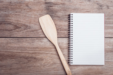 Cooking wooden spatula and lined paper on wooden table top view