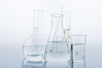 Different laboratory glassware with water and empty with reflection on white background