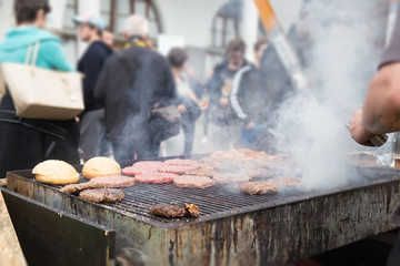 Wall Mural - Chef making beef burgers outdoor on open kitchen international food festival event. Street food ready to serve on a food stall.