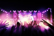 © ifriday - Audience with hands raised at a music festival and lights streaming down from above the stage. live concert, music festival, happy youth, luxury party, landscape exterior.