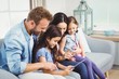 © WavebreakMediaMicro - Happy family looking in digital tablet on sofa