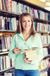 © Syda Productions - happy student girl or woman with book in library