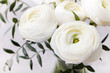 White ranunculus flowers in a glass vase Grey background