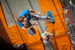 © anatoliy_gleb - Climber with climbing equipment hanging on a rope, falling down an indoor rock-climbing wall, view from above