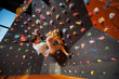 © anatoliy_gleb - Athletic man climbing up on practice wall in gym with climbing shoes, side view. Bouldering
