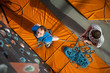 © anatoliy_gleb - Man with climbing equipment standing on the ground looking up at indoor. Rock climber, view from above