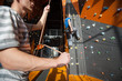 © anatoliy_gleb - Strong male hands holding a rope with special equipment, belaying the climber on rock wall indoors. Focus on left hand