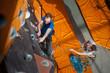 © anatoliy_gleb - Strong man practicing climbing on rock wall indoors, view from above. Man standing on the ground insuring the climber