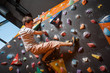 © anatoliy_gleb - Athletic man climbing up on practice wall in gym with climbing shoes