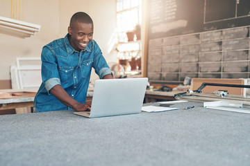 Small business owner of African descent using laptop in workshop