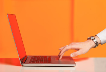 Businessman pressing modern laptop computer on colorful backgrou
