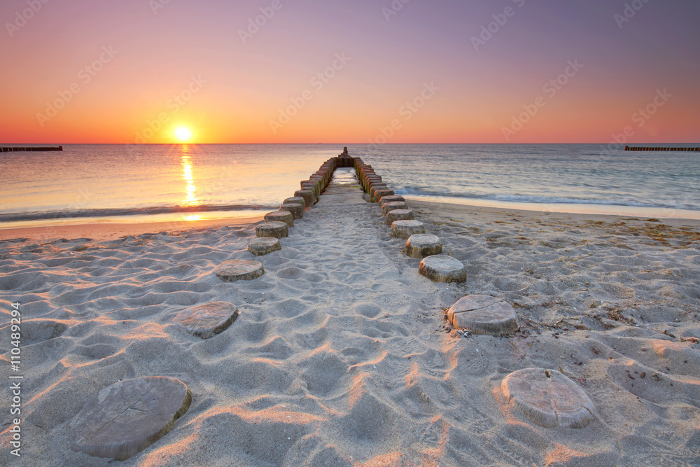 Fotovorhang - lange hölzerne Buhnen am Strand, Sonnenuntergang am Meer