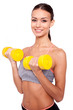 Weight training. Beautiful young sporty woman in tank top exercising with dumbbells and smiling while standing against white background.