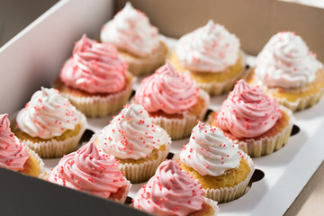 Cupcake packaging, delivery box, vanilla cupcakes with pink and white cream, selective focus, close up