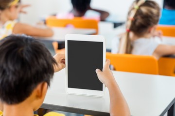 Rear view of pupils using tablet pc in classroom