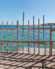 Seaside brown and green wooden fences against aqua ocean and blue sky