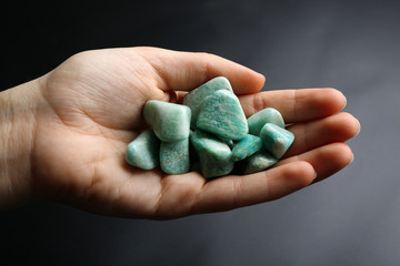 Poster - Woman holding semiprecious stones in her hand on dark grey background