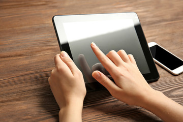 Sticker - Mobile phone and female hands using tablet, on the wooden background