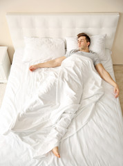 Wall Mural - Young man sleeping alone in white big bed