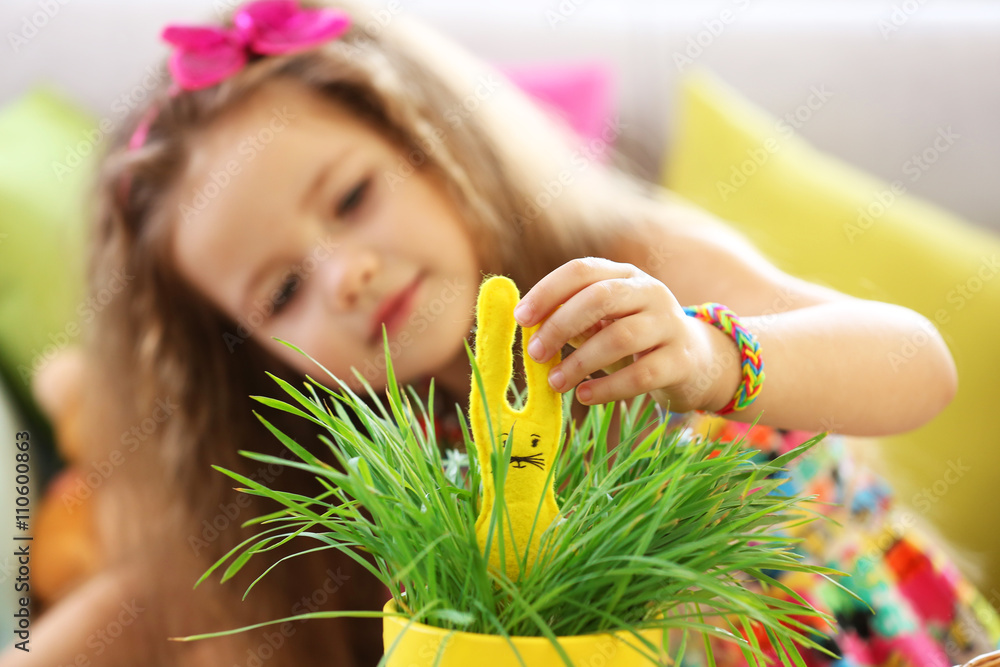 Little girl with plant and Easter rabbit indoors