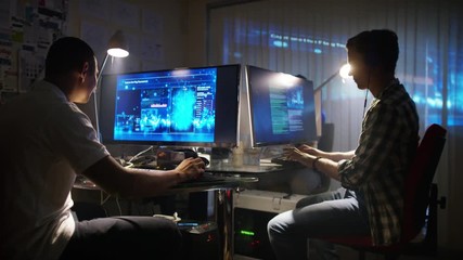  Young creative computer design team working together in dark office.