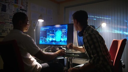  Young creative computer design team working together in dark office.