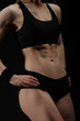 © Anton Gvozdikov - Young muscular woman posing on black
